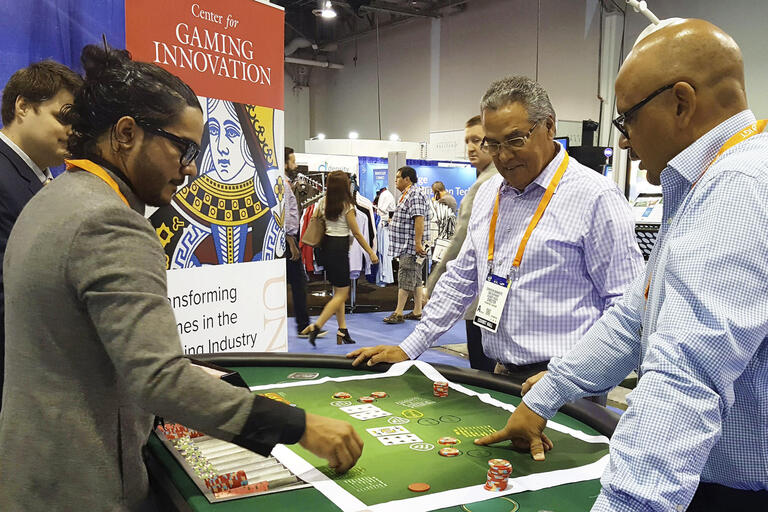 Aron Kock demonstrates his blackjack variant to two onlookers at a gaming convention.