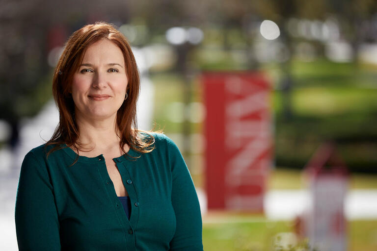 Sheri Palmer poses in front of UNLV banners that are placed around campus.