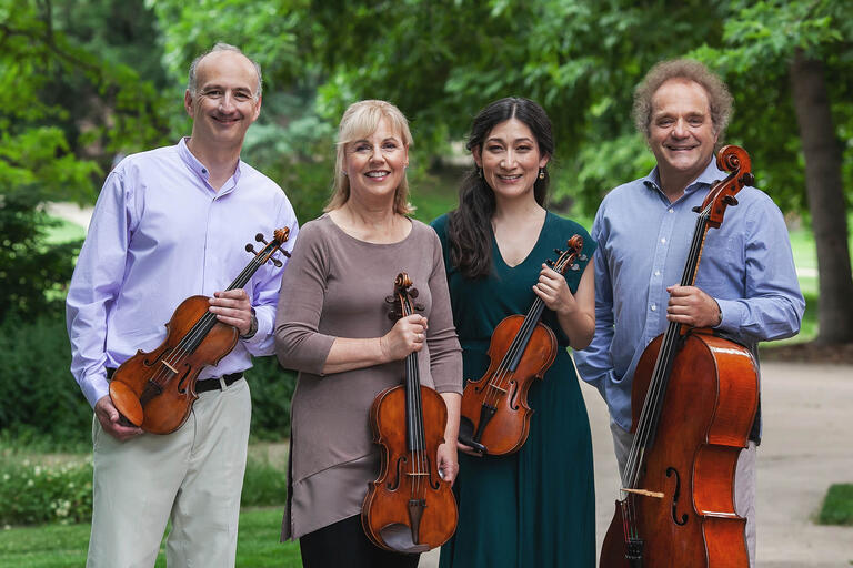Members of the quartet pose outdoors with their instruments.
